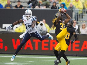 Richard Leonard of the Tiger-Cats pulls in a pass intended for Argonauts’ S.J. Green last night at Tim Hortons Field. The game was delayed for more than two hours because of the storm passing through the region, with the Ticats coming from behind twice to win it and earn their first victory of the season. (The Canadian Press)