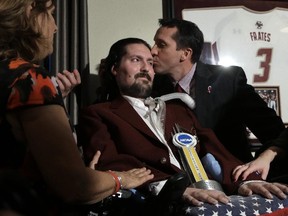 In this Dec. 13, 2016, file photo, former Boston College baseball captain Pete Frates, centre left, receives a kiss from BC baseball coach Mike Gambino after Frates was presented with the 2017 NCAA Inspiration Award, during ceremonies in Frates home in Beverly, Mass. (AP Photo/Steven Senne, File)