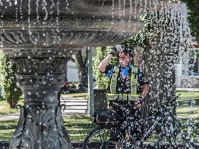 James, a Parking Enforcement officer with the City of Edmonton breaks up his day with lunch, a cool drink and some shade at Giovanni Caboto Park on July 7, 2017. Photo by Shaughn Butts / Postmedia