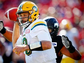 Edmonton Eskimos quarterback Mike Reilly scrambles to throw a pass as he is under pressure from James Vaughters of the Calgary Stampeders during CFL football on Monday, September 4, 2017.