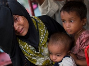 An exhausted Rohingya woman arrives with her children at Kutupalong refugee camp after crossing from Myanmmar to the Bangladesh side of the border, in Ukhia, Tuesday, Sept. 5, 2017. The family said they had lost several family members in Myanmar. Tens of thousands of Rohingya Muslims, fleeing the latest round of violence to engulf their homes in Myanmar, have been walking for days or handing over their meager savings to Burmese and Bangladeshi smugglers to escape what they describe as certain death. (AP Photo/Bernat Armangue)