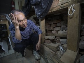 Retired restaurant owner Donald Lee looks at the damage caused by firefighters who rescued a man stuck between his building and the one next door. (STAN BEHAL, Toronto Sun)