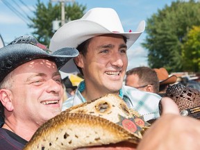 Prime Minister Justin Trudeau, right, poses for photographs with members of the public during a visit to the annual Saint-Tite western festival in Saint-Tite, Que., Friday, September 8, 2017. THE CANADIAN PRESS/Graham Hughes