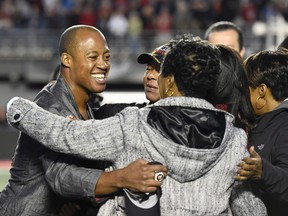 Former Redblacks quarterback Henry Burris hugs his family during a ceremony honouring his career during halftime of a CFL game in Ottawa on Saturday, Sept. 9, 2017. (Justin Tang/The Canadian Press)