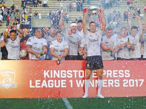 Toronto Wolfpack captain Craig Hall hoists the trophy yesterday as the beer-soaked first-year rugby league team celebrates capturing the Kingstone Press League 1 title and promotion to the English second tier after defeating the Barrow Raiders 26-2 at Toronto’s Lamport Stadium. (Neil Davidson, Canadian Press)