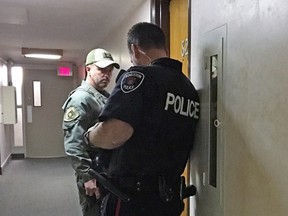 Kingston Police constables Jeff Dickson, left, and Steve Koopman listen outside the door during a domestic noise complaint call for service on Saturday. (Steph Crosier/The Whig-Standard)