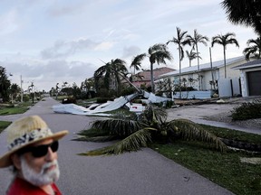 A fallen palm tree and a roof litters a street as Rick Freedman checks his neighborhood's damage from Hurricane Irma in Marco Island, Fla., Monday, Sept. 11, 2017. (AP Photo/David Goldman)
