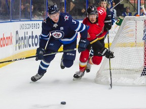 Winnipeg Jets Tucker Poolman (left) and Calgary Flames Spencer Foo give chase for the loose puck during NHL pre-season hockey action at the Young Stars Classic held at the South Okanagan Events Centre in Penticton, B.C., Sept., 11, 2017. Richard Lam/Postmedia