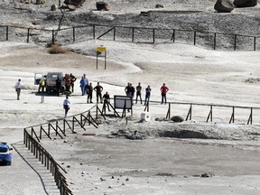 Rescuers stand on the site where three people reportedly died when they fell into a crater in a steamy volcanic field in Pozzuoli, near Naples, Italy, Tuesday, Sept. 12, 2017. Italian news reports say an 11-year-old Italian boy and his parents died in a steamy volcanic field near Naples. ANSA said the parents tried to rescue the boy after he entered an off-limits area at the Solfatara Crater in Pozzuoli, and was overcome by gases, losing consciousness. (Ciro Fusco/ANSA via AP)