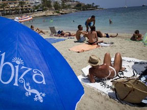 People sunbathe on the beach on Ibiza island. (JAIME REINA/Getty Images)