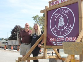 Linda Rouse, owner of The Rustic Wine Cellar, and her partner Miles Wilson stand beside the temporary sign they put up outside their business. New draft sign bylaws were presented at the city’s reference committee Monday. Some owners are worried that it may affect when and where they can put signs advertising their business. (Laura Broadley/Times-Journal)