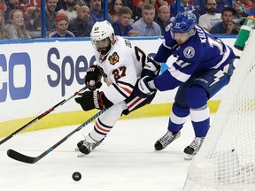 Chicago Blackhawks defenceman Johnny Oduya and Tampa Bay Lightning left wing Alex Killorn chase a loose puck during an NHL game on March 27, 2017. (THE CANADIAN PRESS/AP, Chris O'Meara)