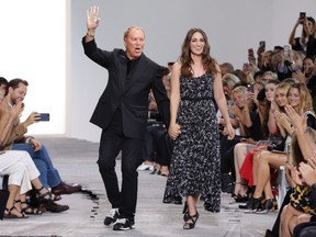 Designer Michael Kors, left, and singer Sara Bareilles, who performed during his show, walk the runway after his Spring 2018 collection was modeled, during Fashion Week in New York, Wednesday, Sept. 13, 2017. (AP Photo/Richard Drew)