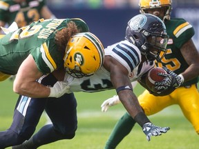 Argonauts running back James Wilder Jr., gets tackled by Alex Hoffman-Ellis of the Eskimos in the first half of yesterday’s tilt. (The Canadian Press)