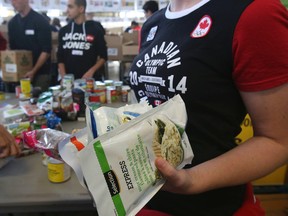 Canadian Olympians sort and pack non-perishable items along with other volunteers on October 12, 2013 at the Daily Bread Food Bank in Toronto. (Veronica Henri/Toronto Sun)