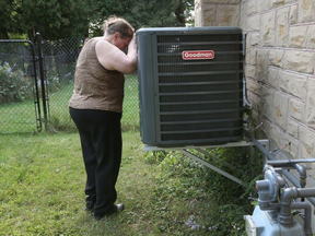 Janet Smith stands beside her air conditioner outside her home in Ottawa. (TONY CALDWELL, Postmedia)