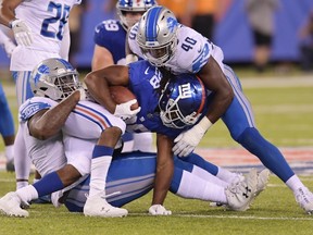 New York Giants' Paul Perkins (28) is tackled by Detroit Lions' A'Shawn Robinson (91) and Jarrad Davis (40) during the second half of an NFL football game, Monday, Sept. 18, 2017, in East Rutherford, N.J. The Lions won 24-10. (AP Photo/Bill Kostroun)