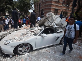 A man stands next to a car crashed by debris from a damaged building after a quake rattled Mexico City on September 19, 2017. (ALFREDO ESTRELLA/AFP/Getty Images)