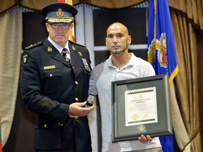 OPP Commissioner Vincent Hawkes presents a bravery award to Jonathan Lumsden, a motorist who ran across three lanes of Highway 403 last November to help three people involved in a crash.  (MORRIS LAMONT, The London Free Press)