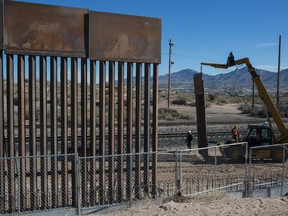 Workers use a crane to lift a segment of a new fence into place on the U.S. side of the border with Mexico, where Sunland Park, New Mexico, meets the Anapra neighbourhood of Ciudad Juarez, Mexico, on March 30, 2017. (Rodrigo Abd/AP Photo)