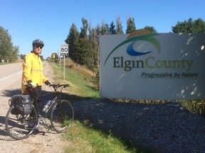 Clayton Watters stands beside the County of Elgin sign during his ride across the county last year. This will be the third year of the ride but the first time Watters is joined by fellow cyclists. The official name of the event is Ride Across County of Elgin. (Contributed photo)
