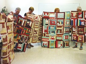 Ladies from the Quilter's guild hold up the slab quilts they made.