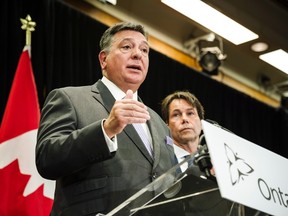 Minister of Health and Long-Term Care Eric Hoskins (right) looks on as Minister of Finance Charles Sousa speaks during a news conference where they detailed Ontario's solution for recreational marijuana sales, in Toronto on Friday, Sept. 8, 2017. (THE CANADIAN PRESS/PHOTO)