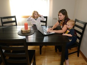 Erin DeCoste works at the kitchen table while looking after her son Evan DeCoste Wilson, 19 months, and daughter Claire DeCoste Wilson, 4. (MORRIS LAMONT, The London Free Press)