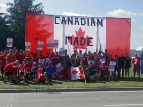 Striking Cami workers show the flag on the picket line outside the General Motors assembly plant in Ingersoll Thursday. (HEATHER RIVERS/Postmedia News)