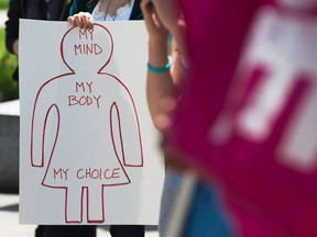 A protester holds a pro-choice sign at Victoria Park, in Halifax, during a demonstration for access to abortion services on the one-year anniversary of the death of Dr. Henry Morgentaler, May 29, 2014. (Andrew Vaughan/The Canadian Press/Files)
