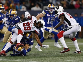 Redblacks’ William Powell gets tackled by a trio of Blue Bombers defenders during last night’s game at Investors Group Field. (THE CANADIAN PRESS)