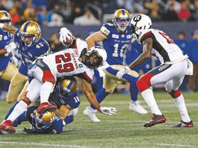 Redblacks’ William Powell gets tackled by Jovan Santos-Knox (45), T.J. Heath (23) and Taylor Loffler (16) of the Bombers last night at Investors Group Field. The Bombers won 29-9. (John Woods, Canadian Press)