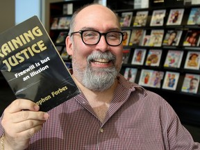 Author Stephan Forbes holds ups copy of his book, Raining Justice, at the Belleville Public Library on Saturday September 23, 2017 in Belleville, Ont. Tim Miller/Belleville Intelligencer/Postmedia Network