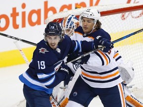 Winnipeg Jets' Nic Petan (19) and Edmonton Oilers' Mitch Callahan (15) jostle for position in front of goaltender Laurent Brossoit (1) during first period NHL pre-season game action in Winnipeg on Wednesday, September 20, 2017. THE CANADIAN PRESS/John Woods