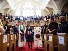 Attendees stand during a funeral service for Arnold Chan, former MP for Scarborough-Agincourt, in Toronto on Saturday, September 23, 2017. (Christopher Katsarov/THE CANADIAN PRESS)