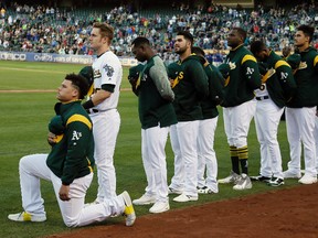 Oakland Athletics catcher Bruce Maxwell kneels during the U.S. National Anthem before the start of a baseball game against the Texas Rangers Saturday, Sept. 23, 2017, in Oakland, Calif. Bruce Maxwell of the Oakland Athletics has become the first major league baseball player to kneel during the national anthem. (AP Photo/Eric Risberg)