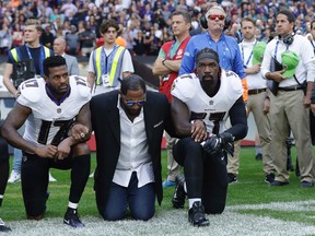 Baltimore Ravens wide receiver Mike Wallace, from left, former player Ray Lewis and inside linebacker C.J. Mosley lock arms and kneel down during the playing of the U.S. national anthem before an NFL football game against the Jacksonville Jaguars at Wembley Stadium in London, Sunday Sept. 24, 2017. (AP Photo/Matt Dunham)