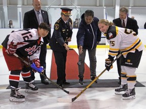 Team captains Zhang Mengying, left, and Emma Smith take part in a ceremonial puck drop with city councillor Gary Oosterhof, Kingston Police Deputy Chief Antje McNeely, Qiqihar Ice Hockey Association president Sun Huanwei and Original Hockey Hall of Fame vice-president Larry Paquette prior to the start of the Two Nations exhibition game at the Invista Centre in Kingston on Saturday, Sept. 23. The Kingston Ice Wolves defeated the Qiqihar Randy Women's Ice Hockey Club 3-2 in a shootout decision. (Steph Crosier/The Whig-Standard/Postmedia Network)