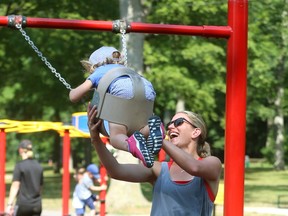 Julia Hall runs through the swings giving her daughter Olivia Harris, 3, a big lift at Springbank Park. (File photo)