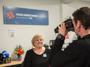 Four Directions Financial Manager Margaret Archibald helps Bryan Kenny with his retinal scan to access his account. Shaughn Butts / Postmedia