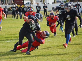 A Whitecourt Cats player gets tackled while running with a football on Sept. 22 (Peter Shokeir | Whitecourt Star).
