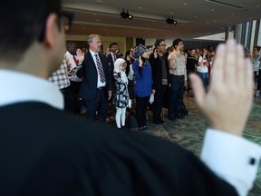 People take the oath as they become Canada's newest citizens during a citizenship ceremony at the National Arts Centre in Ottawa on Monday, Sept. 25, 2017. (THE CANADIAN PRESS/Sean Kilpatrick)
