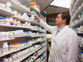 Pharmacist Denis Boissinot checks a bottle on a shelf at his pharmacy in Quebec City on March 8, 2012. (Jacques Boissinot/The Canadian Press/Files)