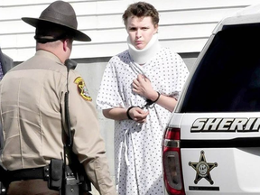 Wearing a hospital gown and neck brace, Zachary Wittke is led into a police transport vehicle following a 2013 arrest in Maine. DAVID LEAMING / KENNEBEC JOURNAL