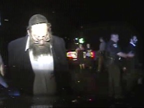 In this Aug. 8, 2017, still frame from dashboard camera video released by the Vermont State Police, Trooper Justin Thompson, left, detains driver Rabbi Berl Fink, while a second officer, right, detains passenger Rabbi Eli Fink, both of of Brooklyn, N.Y. (Vermont State Police via AP)
