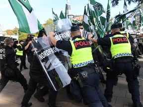 Police officers clash with members of the Nordic Resistance Movement during a demonstration in central Goteborg, Sweden, Saturday Sept. 30, 2017. The authorities say the Nordic Resistance Movement expects some 1,000 people to march Saturday while as many as 10,000 people could counter-demonstrate. (Fredrik Sandberg/TT via AP)