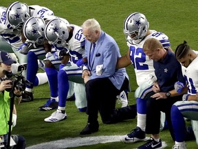 Dallas owner Jerry Jones, middle, and head coach Jason Garrett, second from right, join Cowboys players in kneeling before the Star Spangled Banner is performed before the team's game on Monday night.