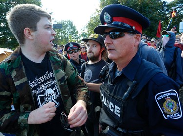 City police escort a man who was punched, seen with a cut on his face, during the protests at Confederation Square on Saturday September 30, 2017 on George St. in Peterborough, Ont. CLIFFORD SKARSTEDT/PETERBOROUGH EXAMINER/POSTMEDIA NETWORK