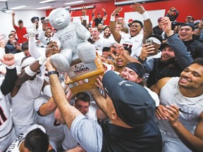 Carleton coach Steve Sumarah hoists the Panda Game trophy in front of his overjoyed players in the dressing room following yesterday's 33-30 win over Ottawa in double overtime. (ASHLEY FRASER, Postmedia Network)