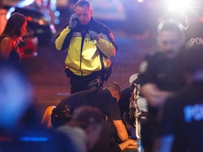 Paramedics work on a person after being struck by a U-Haul truck driven by a man Edmonton Police Service officers say attacked a police officer outside of an Edmonton Eskimos game at 92 Street and 107A Avenue in Edmonton, Alberta on Sunday, October 1, 2017. Ian Kucerak / Postmedia